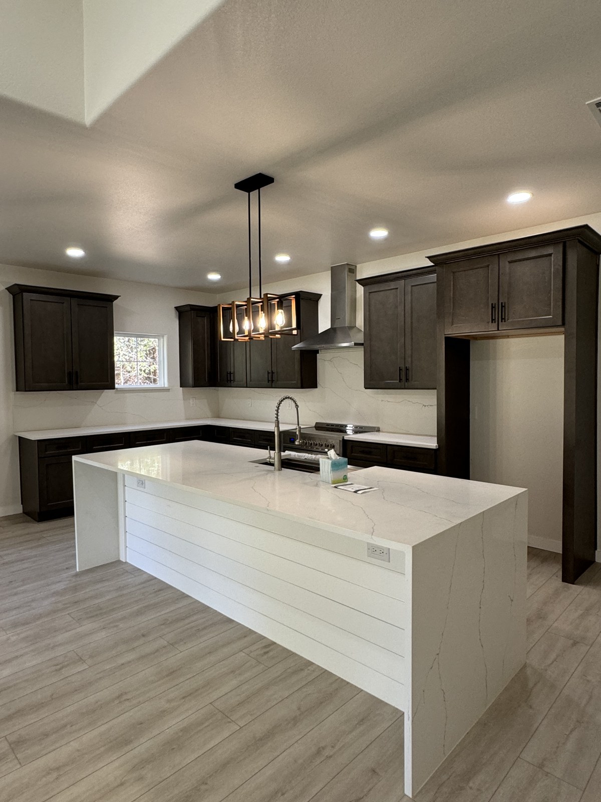 Dark cabinet kitchen with quartz waterfall island
